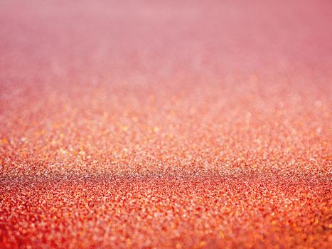 Red abstract background with shiny glitter. Pink festive sparkling macro texture. Holiday backdrop with copy space.