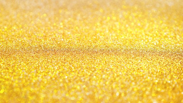 Yellow abstract background with shiny glitter. Golden festive sparkling macro texture. Holiday backdrop with copy space.