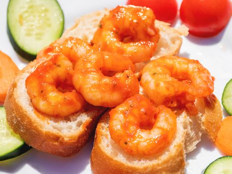 Mediterranean cuisine - freshly cooked shrimps on bread with vegetables. Seafood with cucumbers and tomatoes.