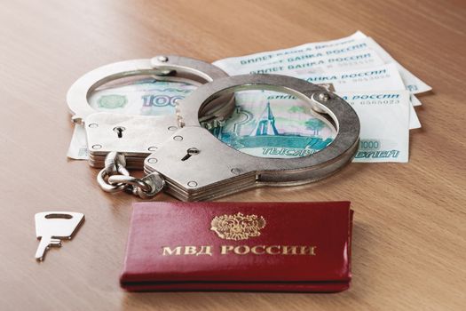 Locked handcuffs, certificate of employee of the Ministry of internal Affairs and Russian banknotes. Legal responsibility and monetary fine for violating isolation during coronavirus COVID-19 quarantine.
