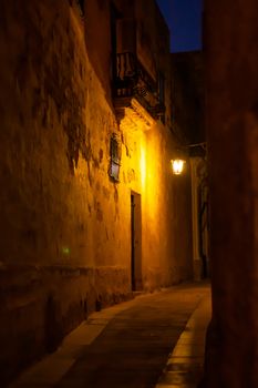 Narrow streets of Mdina, ancient capital of Malta. Night view on illuminated buildings and wall decorations of ancient town.