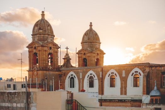 Sunset behind bell towers of Our Lady of Mount Carmel parish church. Gzira, Malta