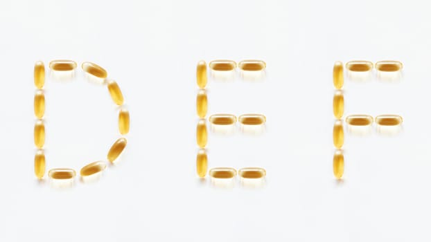 Letters D, E, F made of transparent yellow pills. Part 2 of latin alphabet in medical style. Isolated on white background.