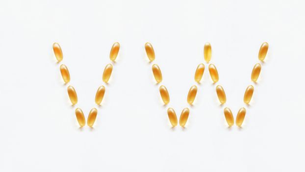Letters V, W made of transparent yellow pills. Part 8 of latin alphabet in medical style. Isolated on white background.