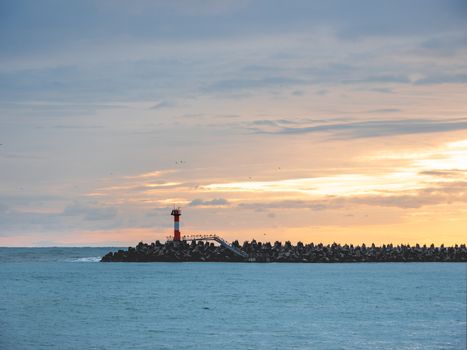 Beautiful sunset over Black sea in Sochi, Russia. Silhouettes of lighthouse and seagulls on the railing.