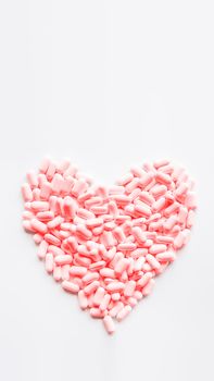 Heart made of pink pills. Top view on drugs in shape of heart. Flat lay white background with copy space.