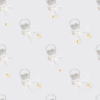 Seamless photo pattern with glass of pure water and yellow pills. Sun shines through transparent liquid on white background and scattered drugs.