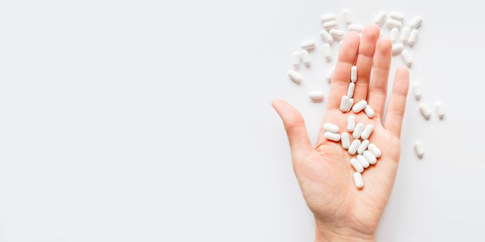 Palm hand full of white scattering pills. Capsules with medicines on light background. Flat lay, top view.