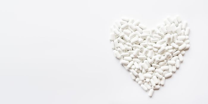 Heart made of white pills. Top view on drugs in shape of heart. Flat lay background with copy space.