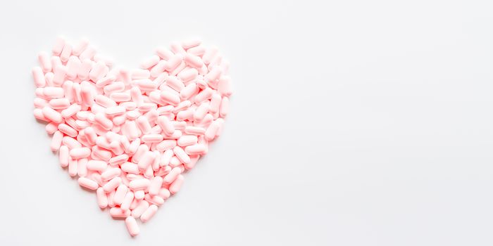 Heart made of pink pills. Top view on drugs in shape of heart. Flat lay white background with copy space.