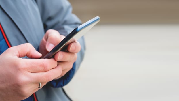 Man's hands with smartphone. Man is texting to somebody. Background with copy space.