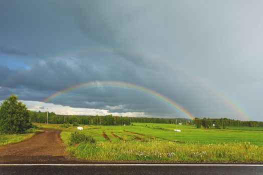 Rainbow over fields. Beautiful summer landscape in sunny day after rain. Finland.