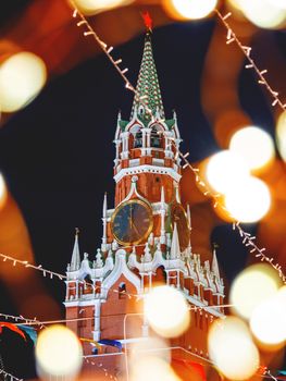 Spasskaya tower of Kremlin, view through light bulbs. Christmas fair on Red square in Moscow. Russia.