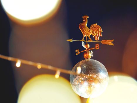 Wind vane in shape of rooster on shiny disco ball. Red Square decorated for New Year and Christmas fair. Moscow, Russia.