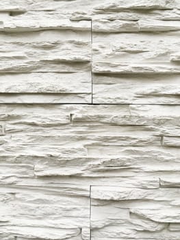 Outdoor wall made of white decorative stones. Stone texture of building wall.