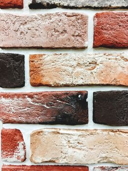 Outdoor wall made of orange and brown bricks with white concrete. Stone texture of building wall.