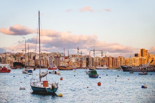 Sliema seaside and moored sailing ships. Yachts and sunset panorama view of Sliema, Malta.