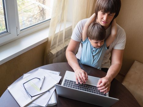 Self-isolation because of coronavirus outbreak. Man is remote working with his little son on self quarantine. Lockdown.