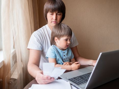 Self-isolation because of coronavirus outbreak. Man is remote working with his little son on self quarantine. Lockdown indoors.