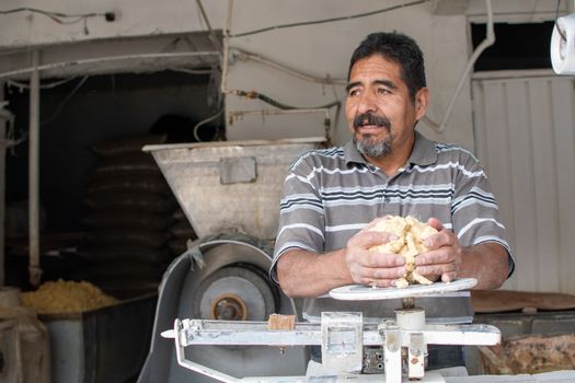 man selling dough in nixtamal mill. A pendulum scale is being used to weigh the dough.