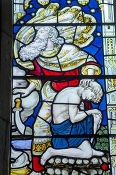 Victorian stained glass window showing Abraham dropping a knife on the command of an angel just as he was about to sacrifice his son Isaac to please God.  Old Testament depicted in an historic window over 100 years old viewed from public place.