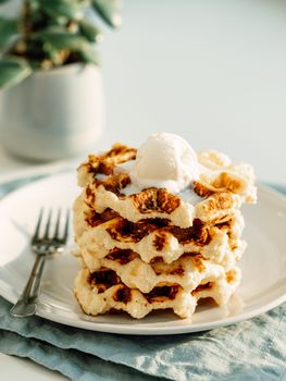 Ricotta cheese chaffles for keto diet. Stack of ricotta and lemon belgian waffles decorated with ice cream scoop. Copy space for text or design. Natural sunset daylight. Vertical.