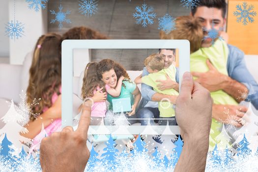 Hand holding tablet pc against snowflakes and fir trees
