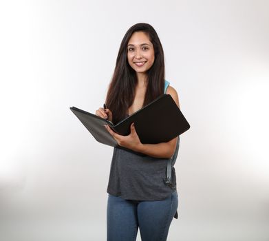 A young student prepares to take notes in her black portfolio while holding her backpack.