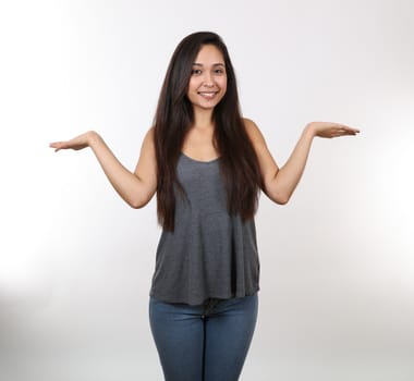 An attractive young female wearing jeans and a grey tank top holds her hands out to her sides.