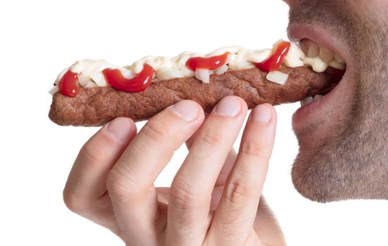 Man eating a frikadel with ketchup, mayonnaise on chopped onions, a Dutch fast food snack called 'frikadel speciaal'