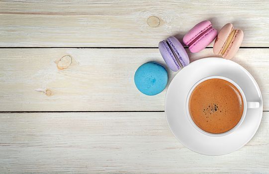 Macaroons and cup with coffee on top on wooden table