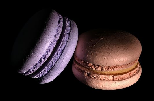 Two macaroons darkened on a black background