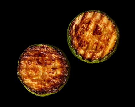 Two slices of zucchini grill on a black background