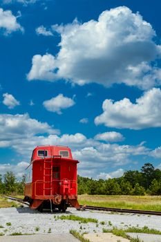 An old red caboose on a track under blue skies