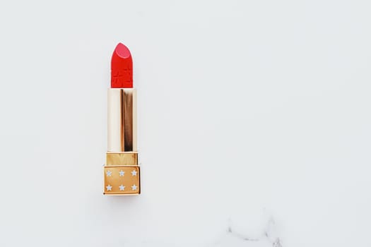 Luxury lipstick in a golden tube on white marble background, make-up and cosmetics concept