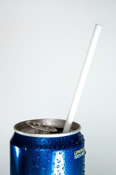 Condensation refreshing water droplets on the fresh cold soft drink can surface, Opened cap with white straw inside.