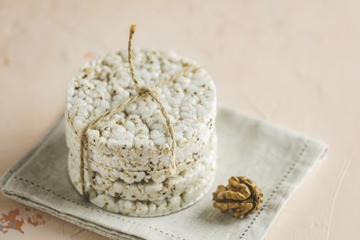 Stack of rice cakes. American puffed rice cakes. Healthy snacks with walnut on light pink concrete surface. Close up