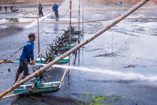 CHACHOENGSAO THAILAND - JULY 13 : Unidentified men control high pressure water jet nozzle to clean the mud at the bottom of the pond on July 13, 2016 to prepare the pond clean, for next time shrimp farming, Chachoengsao, Thailand.