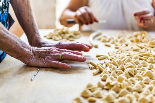 An old woman, while prepare by hands Orecchiette, typical italian pasta.