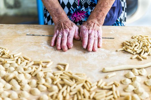 An old woman, while prepare by hands Orecchiette, typical italian pasta.