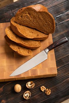 A loaf of bread sliced into slices with a knife on a wooden cutting board