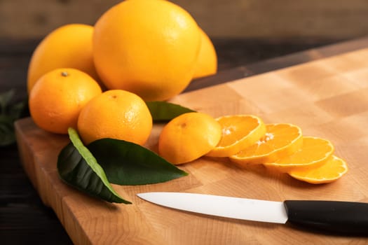 Still life with fruit. Sliced orange and other fruits on a wooden cutting board