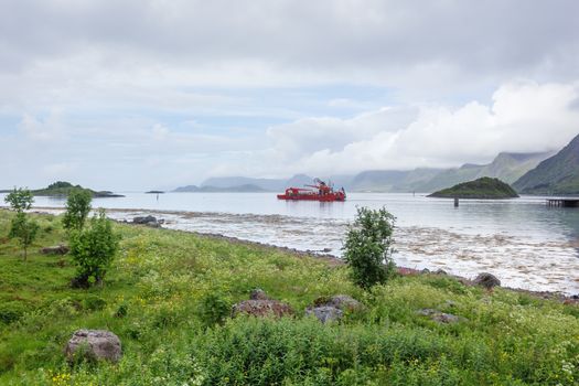 Special purpose ship in the waters of Lofoten archipelago. Typical scandinavian landscape with meadows, mountains and fjords. Lofoten islands, Norway.