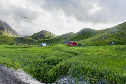 Typical scandinavian landscape with meadows, mountains and village. Lofoten islands, Norway.