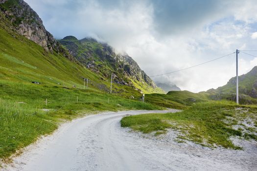 Beautifull scandinavian landscape with meadows, mountains and road. Car trip on Lofoten islands, Norway.