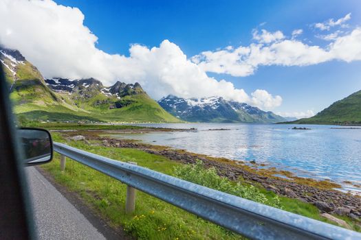 Typical scandinavian landscape with meadows, mountains and fjords. Car trip on Lofoten islands, Norway.