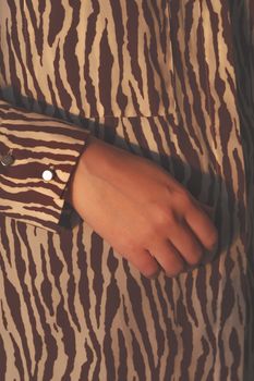 Human hand in evening sun, stylish shirt. Woman body parts, fashionable designer zebra pattern clothes