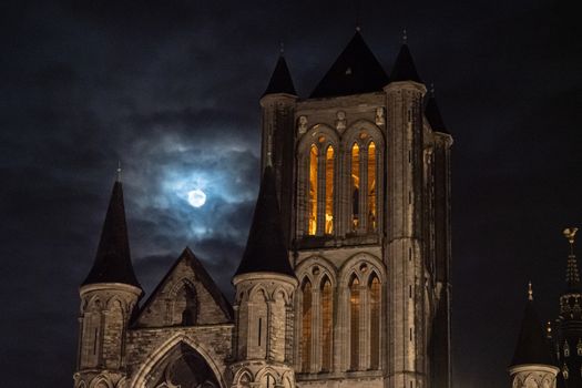 detail of the tower of Saint Nicholas Church, Ghent with the moon