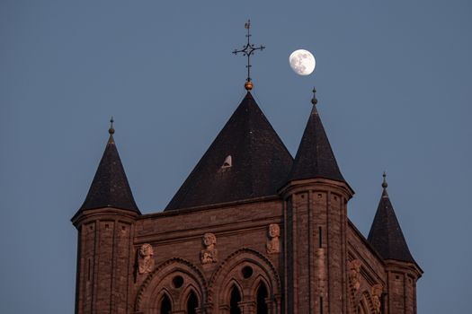 detail of the tower of Saint Nicholas Church, Ghent with the moon