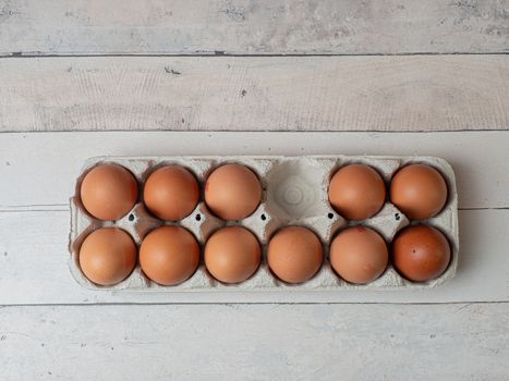 eggs in their box on white wooden background